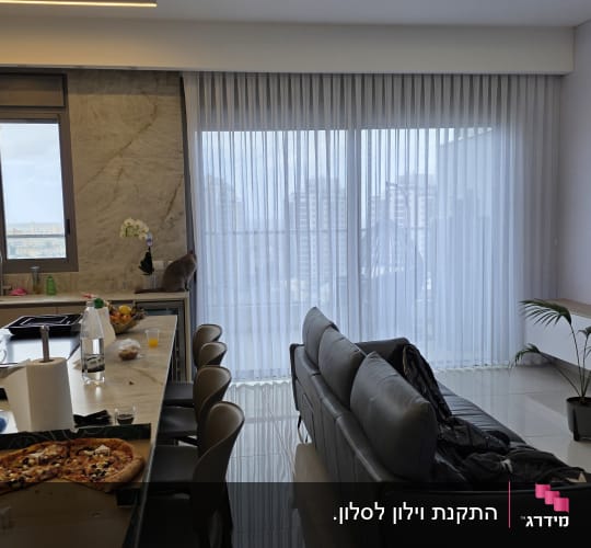 וילון הסטה לבן שקוף מותקן בסלון מודרני מול חלון יציאה למרפסת